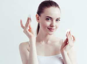 Young woman holding up makeup removing pads.