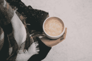 Woman holding a warm drink while standing in the snow.